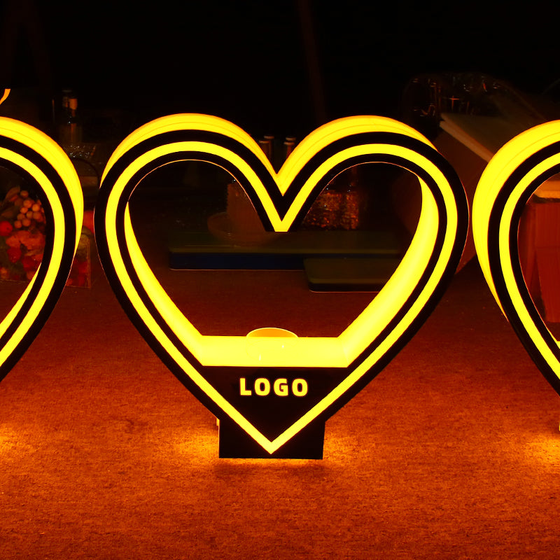 Custom heart-shaped LED bottle presenter with yellow glow lighting and bespoke brand logo for VIP nightclub service.