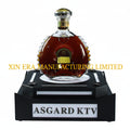 Front view of XIN ERA LED VIP bottle presenter with glowing logo on a dark nightclub background.