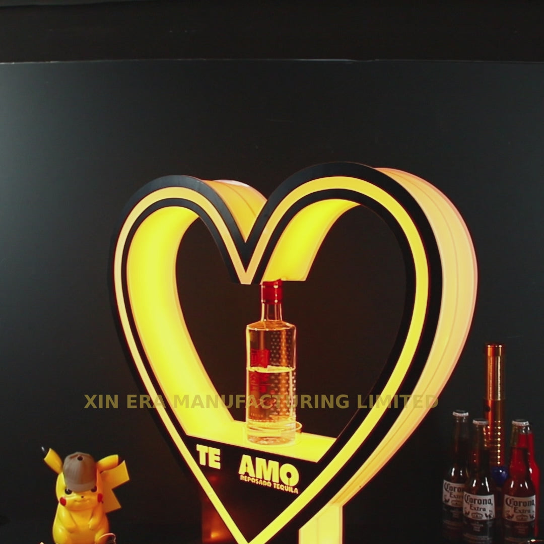 Custom heart-shaped LED bottle presenter with yellow glow lighting and bespoke brand logo for VIP nightclub service.